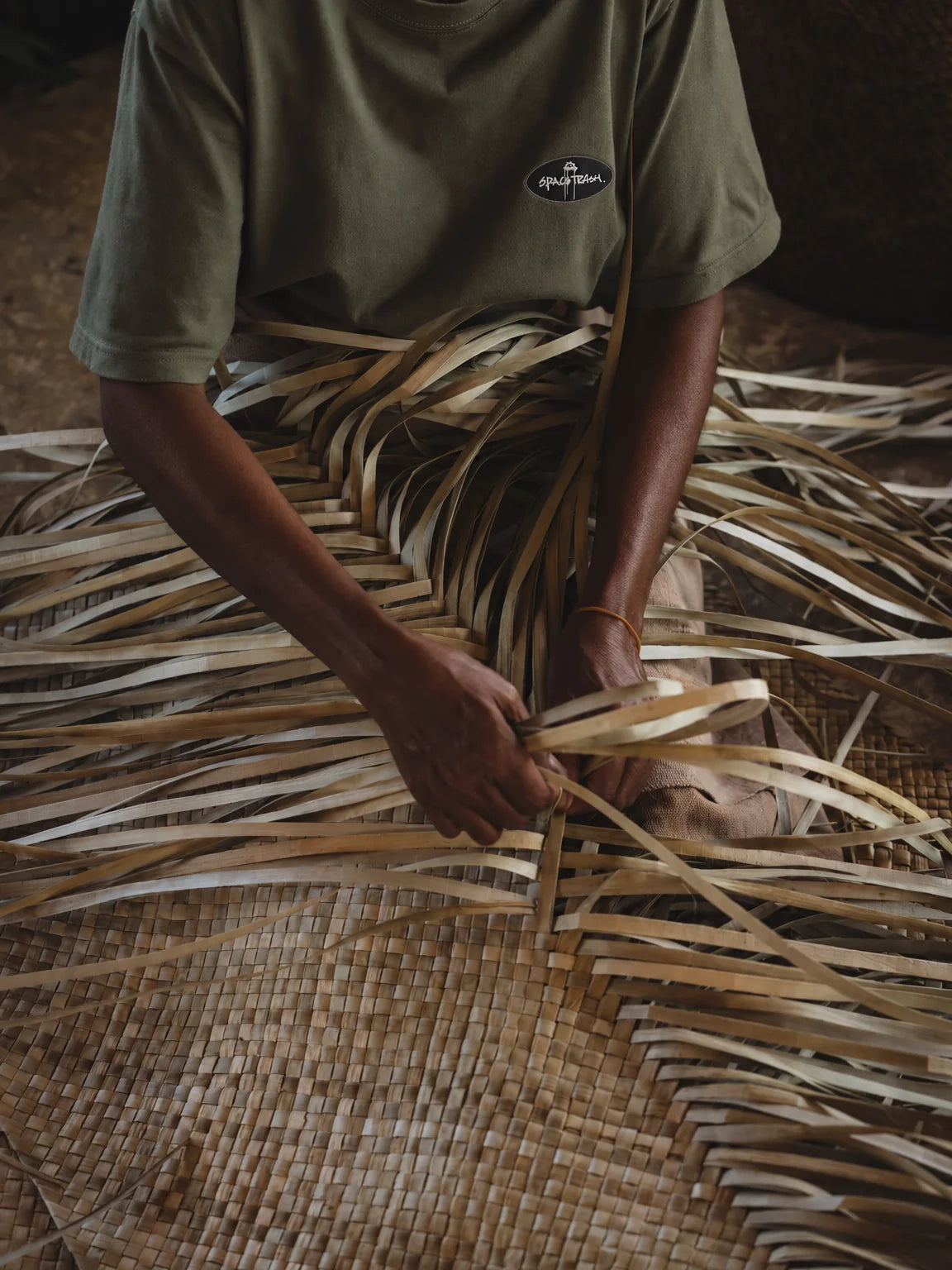An artisan hand-weaving natural bamboo strips